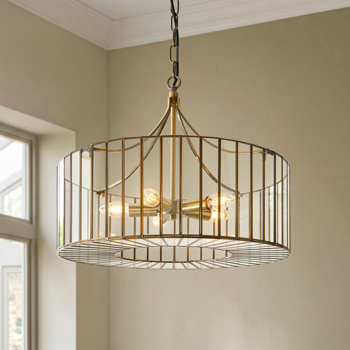 Antalya pendant's brass cage shade with clear glass and three lit candle bulbs