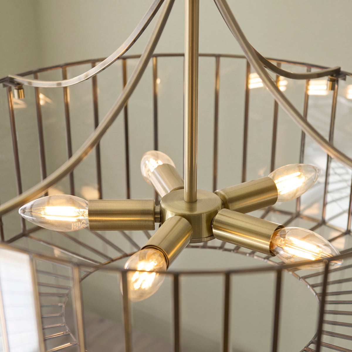 Overhead detail of the Antalya pendant's brass lamp holders and candle bulbs inside the cage