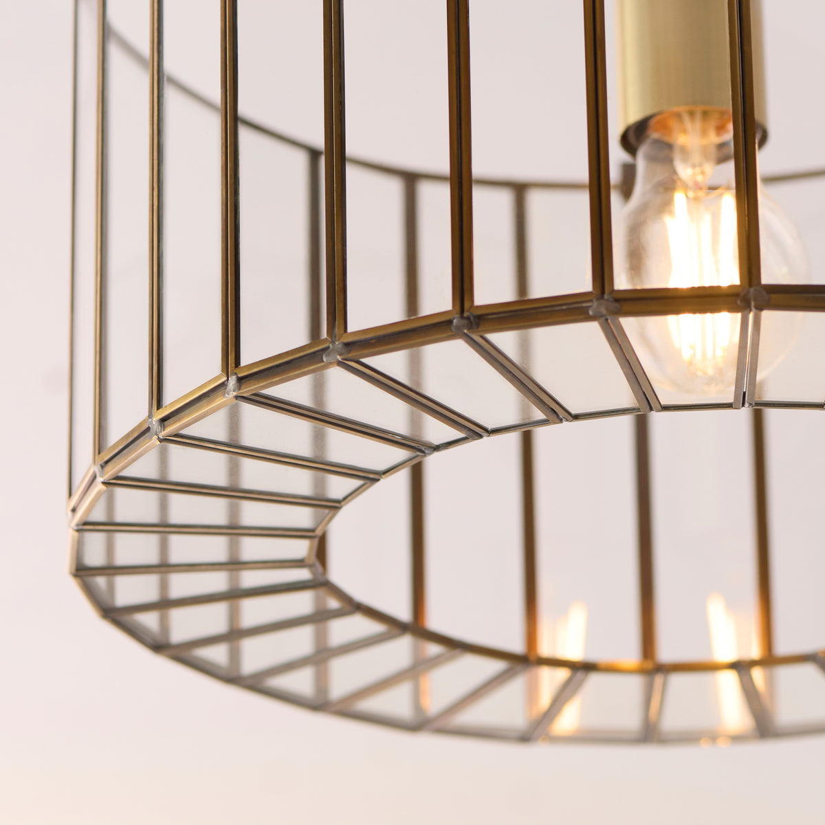 Close-up of the Antalya flush light's slatted brass base ring and lit bulb