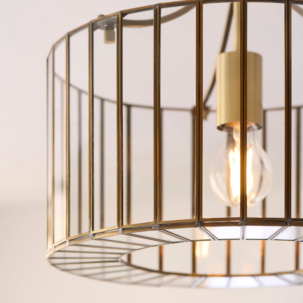 Detail of the Antalya flush light's brass lamp holder, filament bulb and glass panels