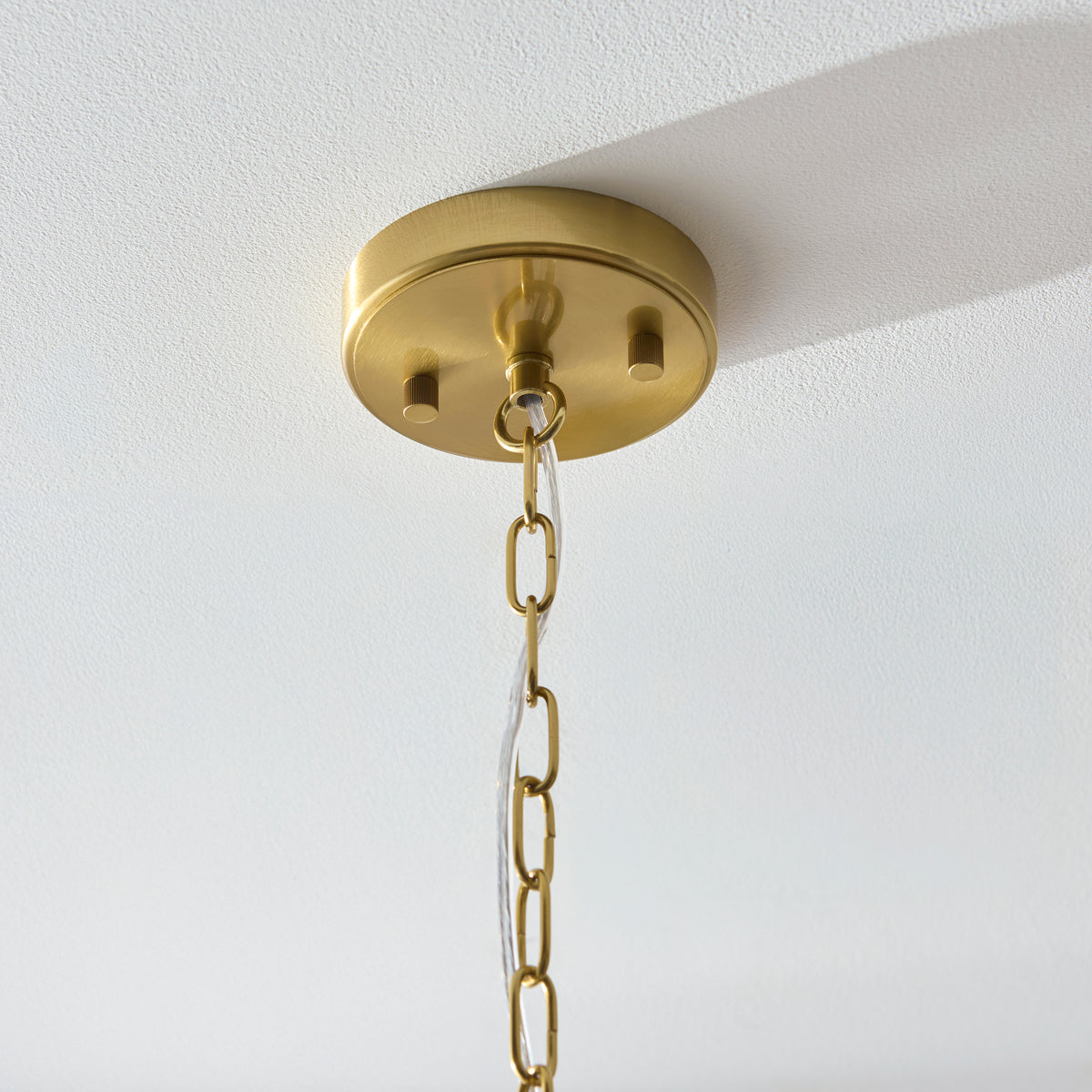 Close-up of the Venice pendant's brushed brass ceiling rose and chain