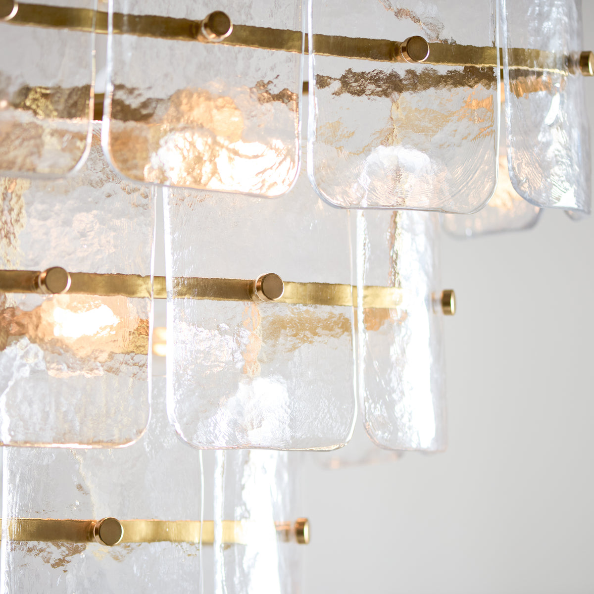 Detail of overlapping textured glass panels pinned to slim brass bars on the Venice chandelier
