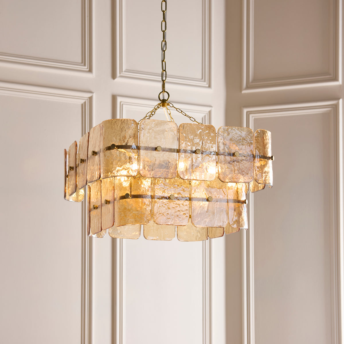 Venice champagne chandelier hanging against pale panelling, tiers of glass panels glowing