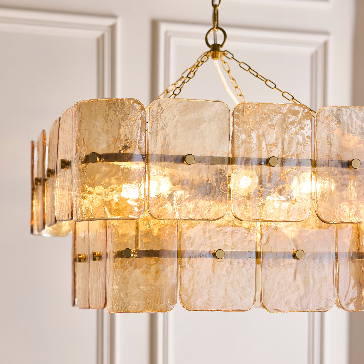 Close-up of the Venice chandelier's champagne handmade glass panels and slim brass bars