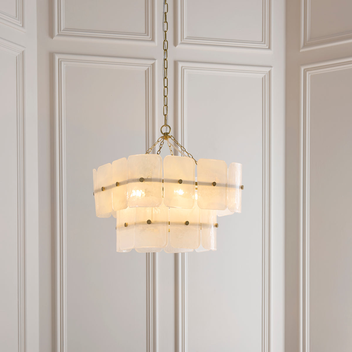 Venice pendant hung against panelled walls, its layered white glass panels held by brass studs