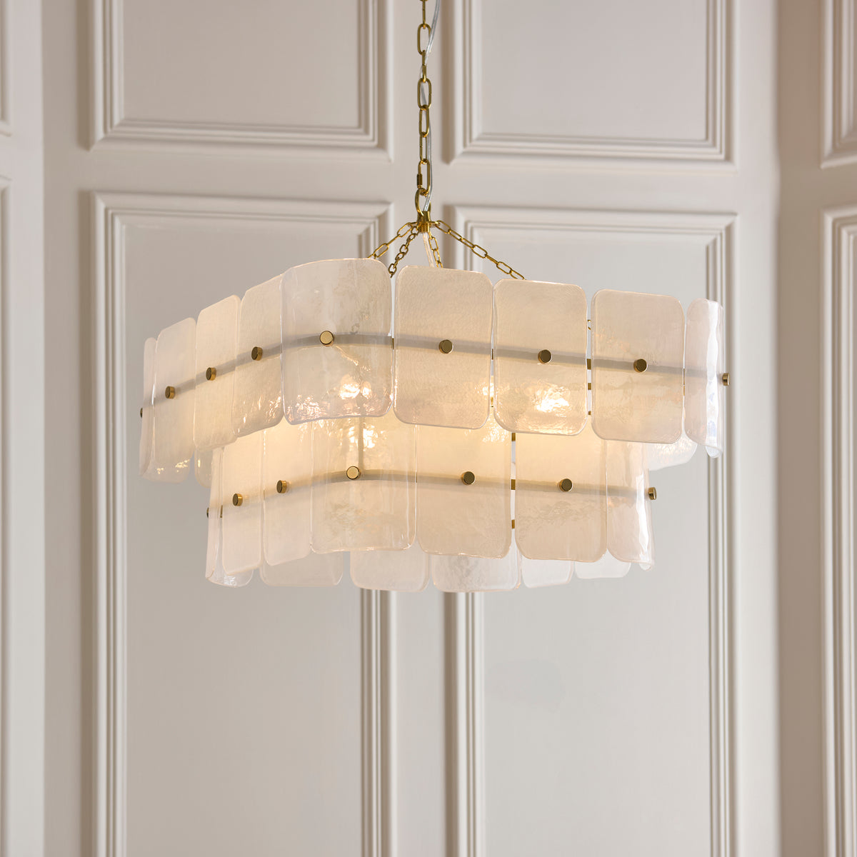 Venice chandelier's layered frosted glass panels lit warmly, suspended from a brass chain frame