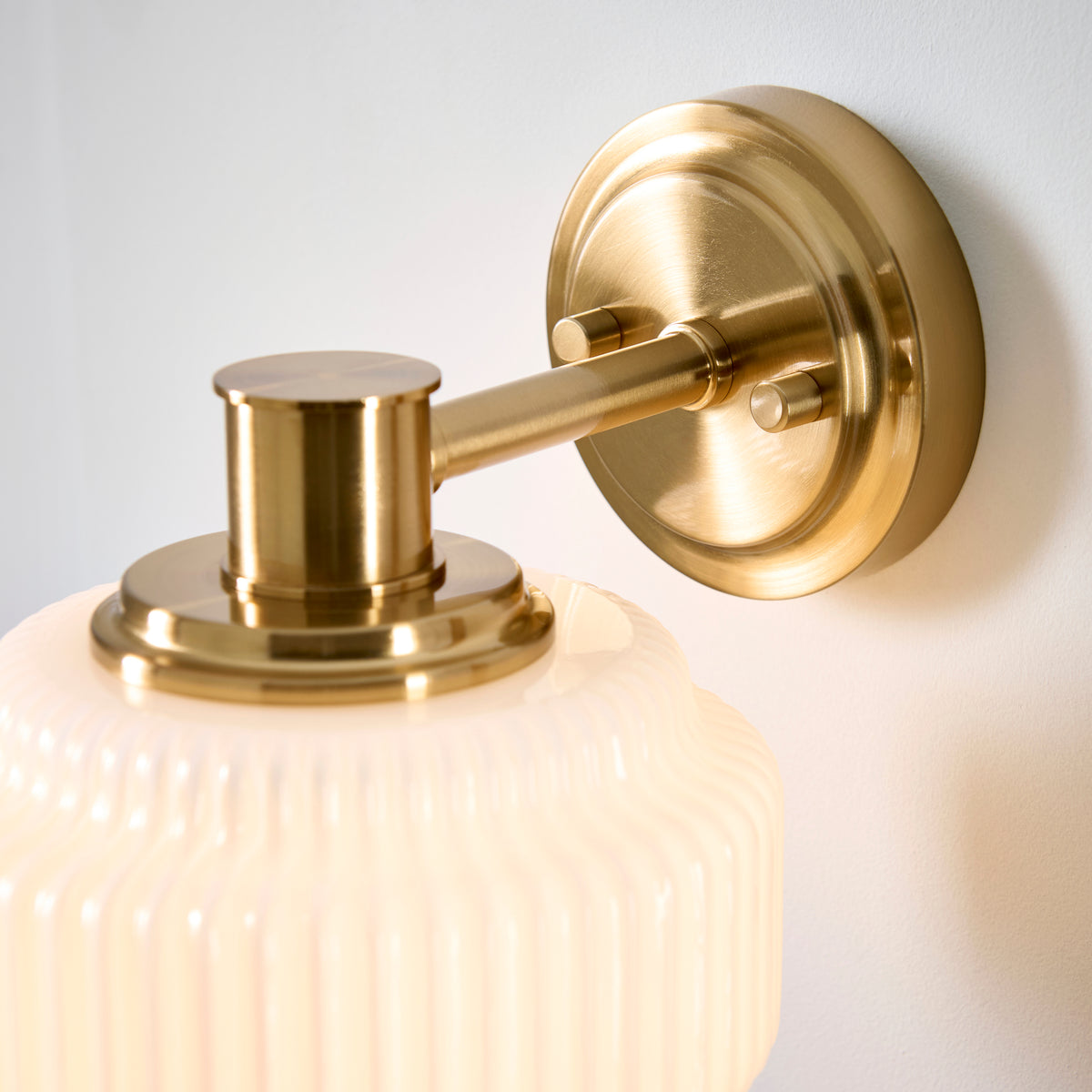 Detail of the Evora wall light's brushed brass arm, backplate and shade collar fixings