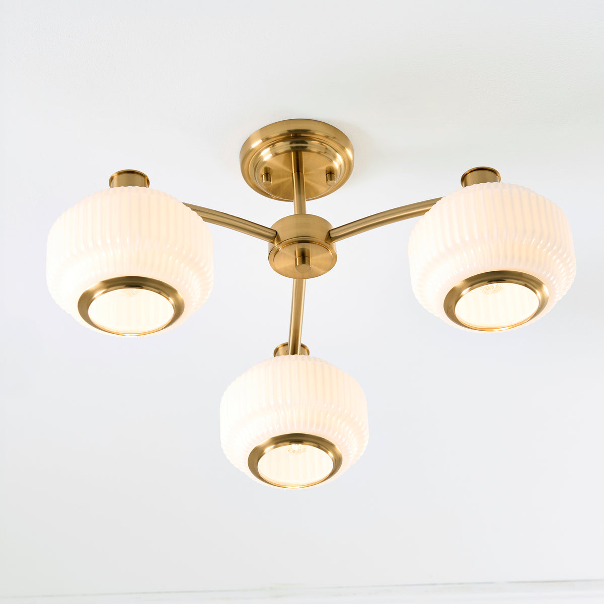 Evora semi flush ceiling light viewed from below, brass arms radiating to three opal shades