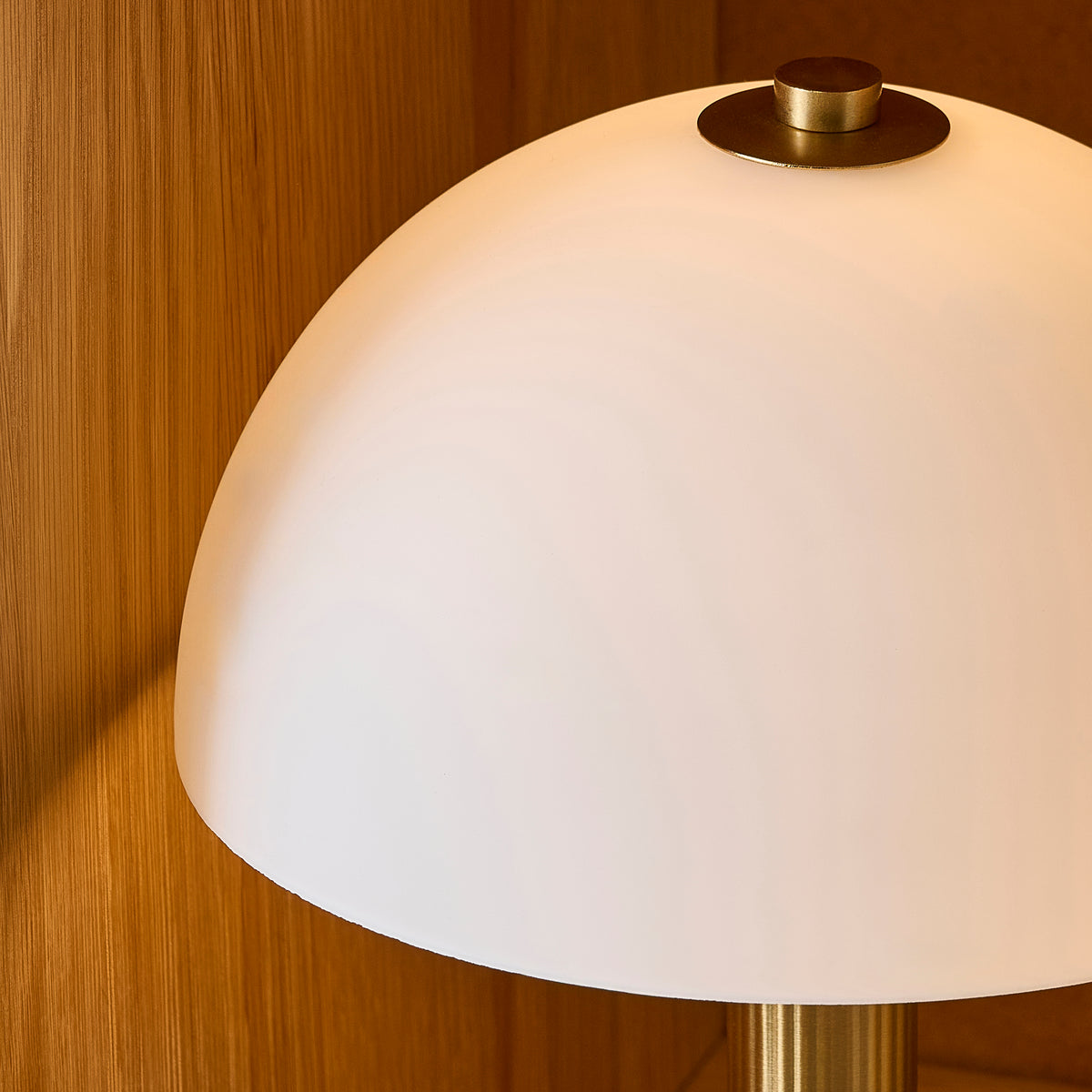 Close-up of the Bridport lamp's opal glass dome and brass finial against warm oak panelling