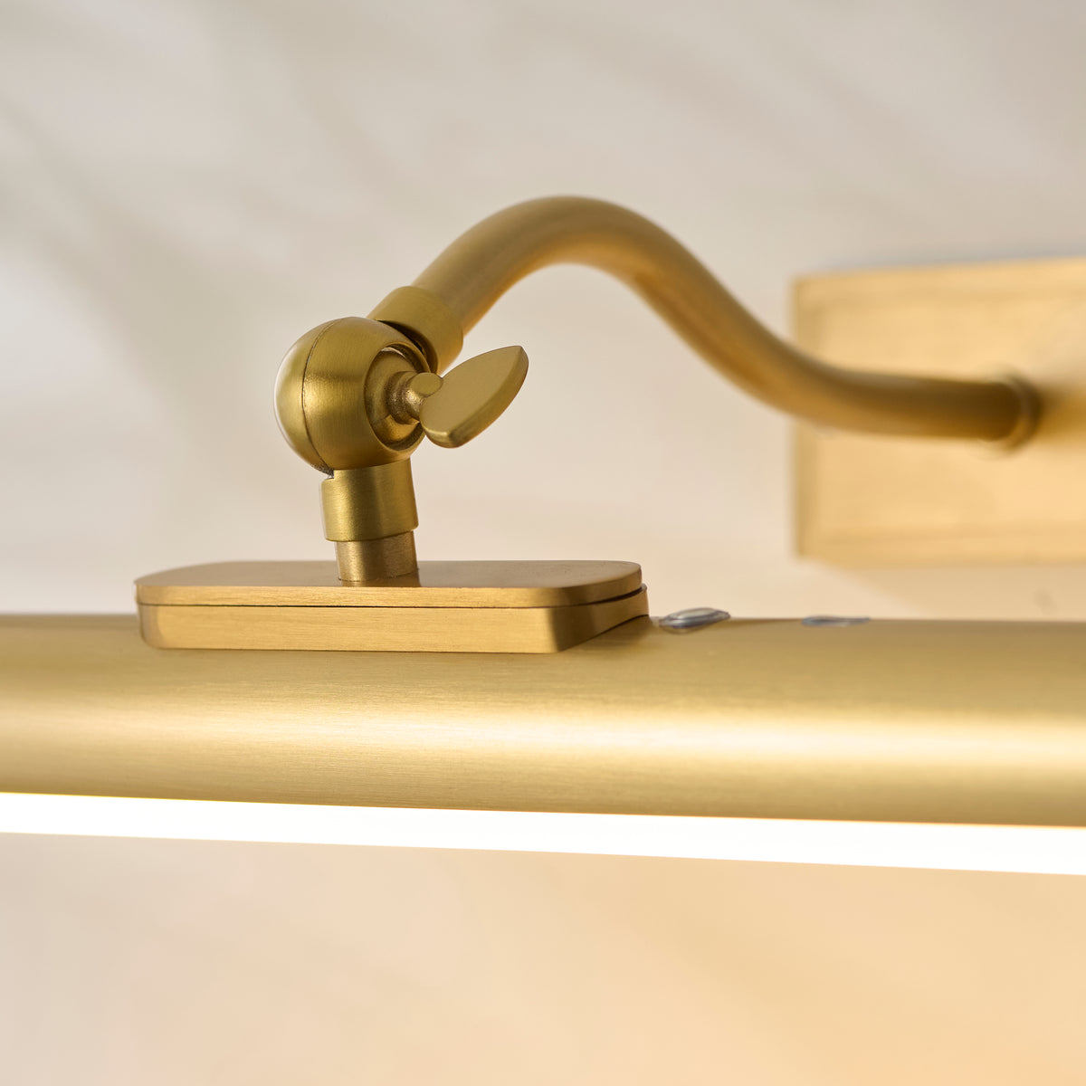 Detail of the Maris picture light's brass tilt knob and swan-neck arm meeting the wall bracket