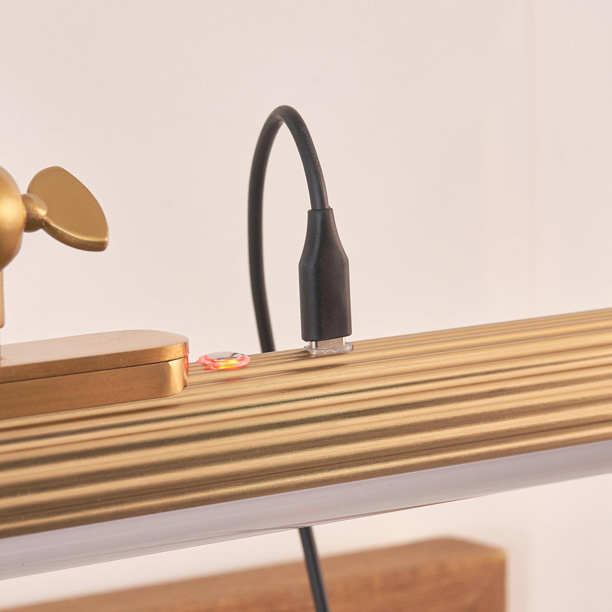 Close-up of the Kindos picture light being charged by a black magnetic USB cable