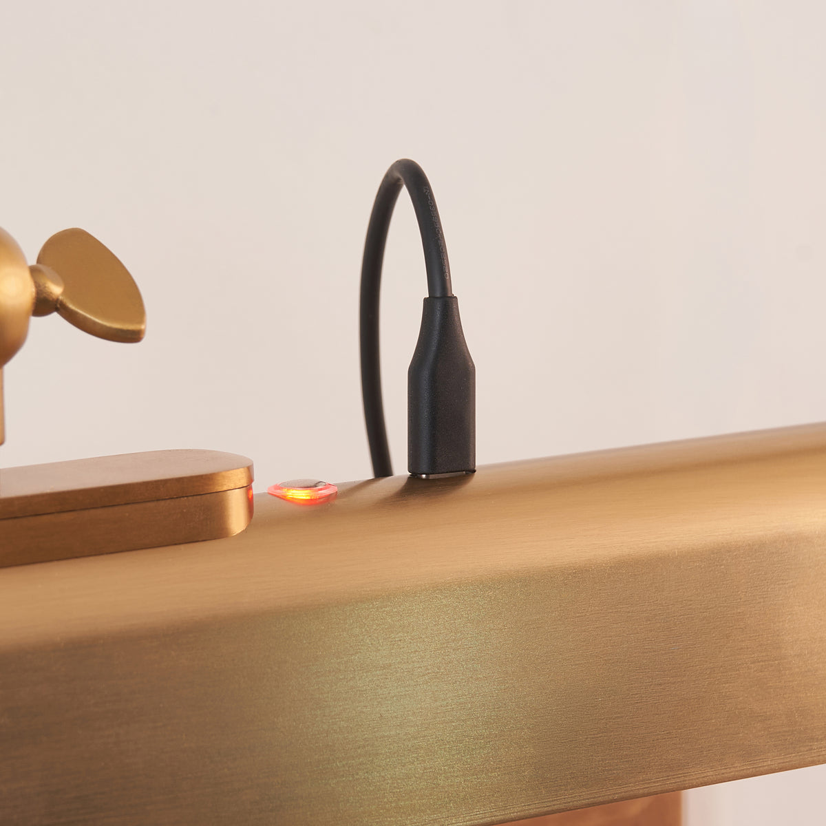 Detail of the Dalyan picture light's magnetic charging point with black cable and red charge indicator