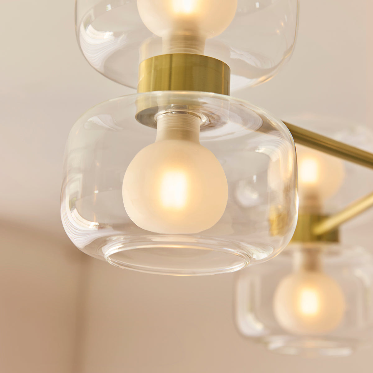 Detail of the Rossano light's clear glass shades and warmly lit frosted globe lamps