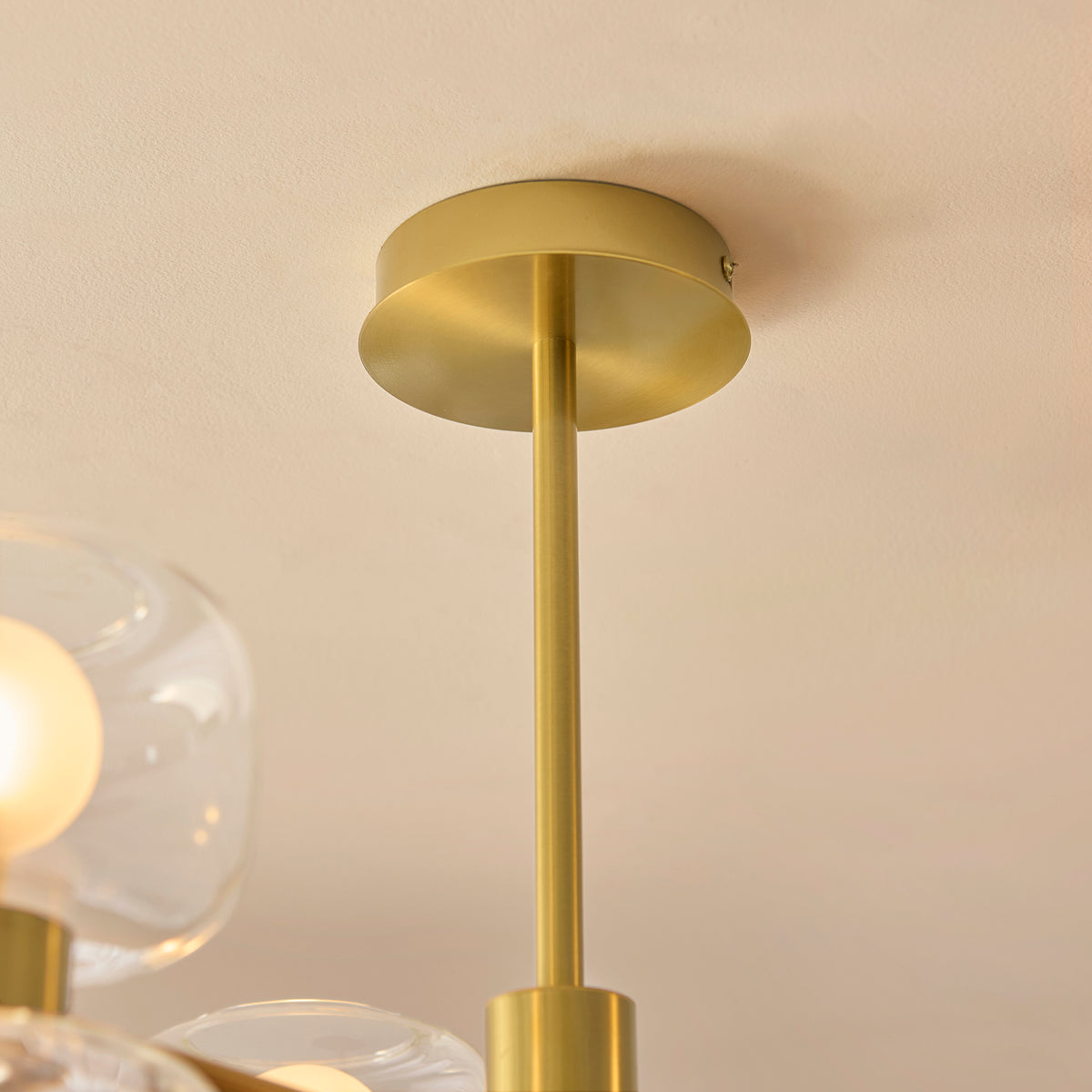 Close-up of the Rossano ceiling light's brass ceiling plate and slim drop rod