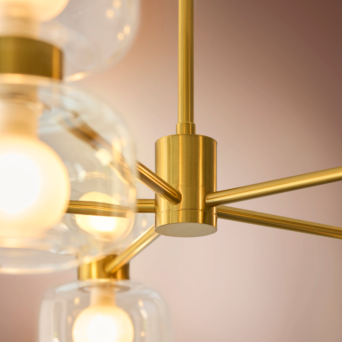 Detail of the Rossano chandelier's brushed brass hub with radiating arms and drop rod
