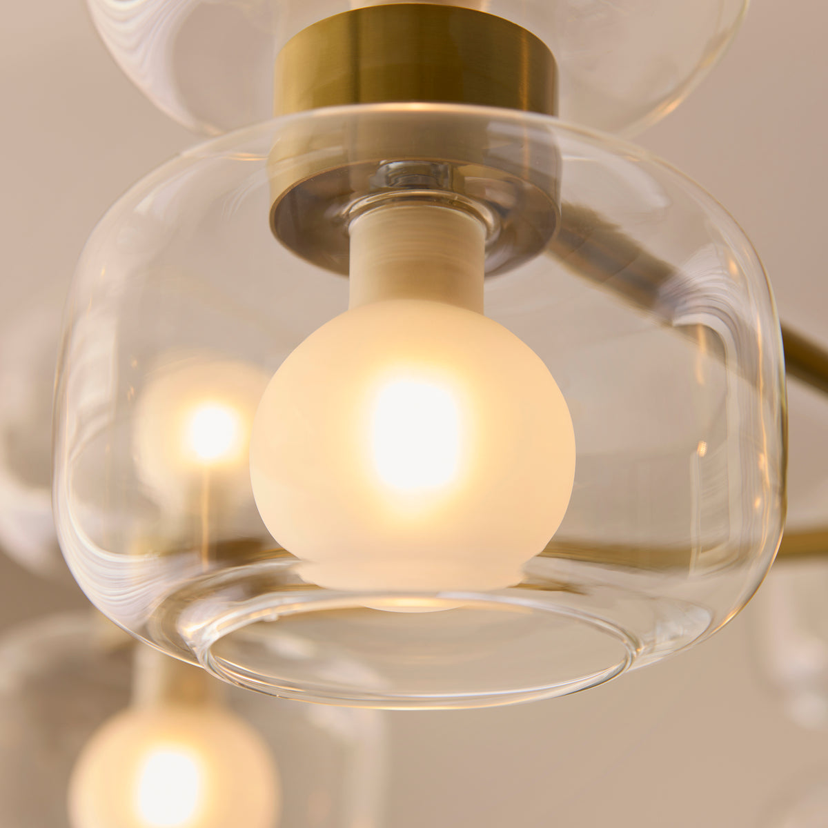 Close-up of one clear glass shade and glowing frosted globe lamp on the Rossano chandelier