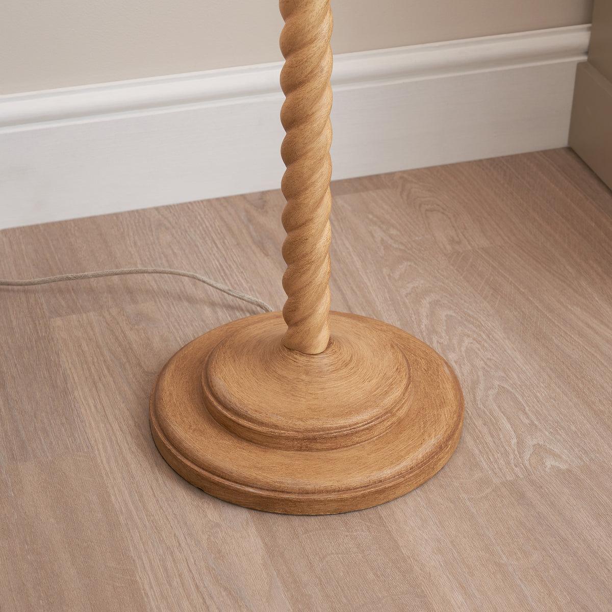 Detail of the round oak effect resin base of the Twist floor lamp on wood flooring