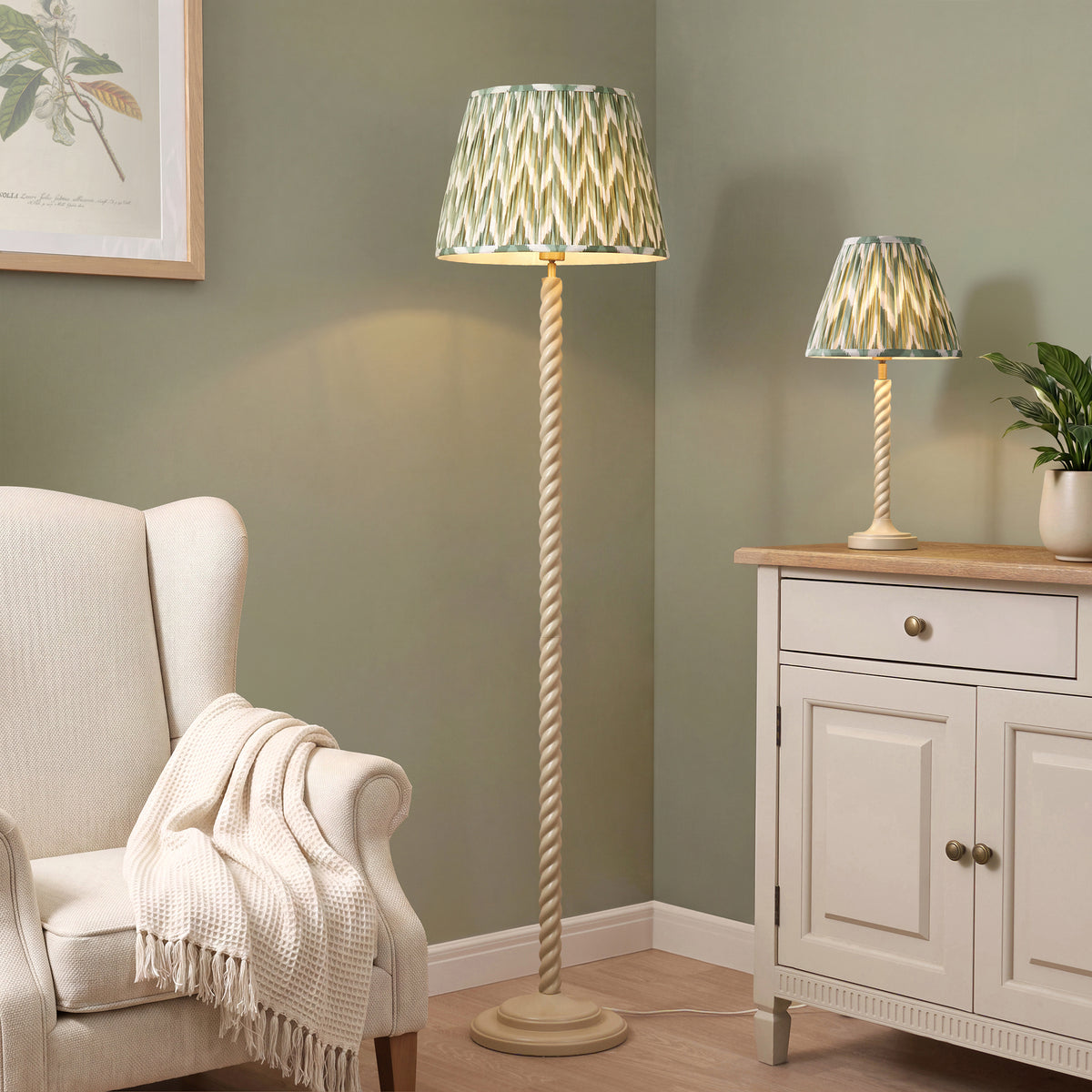 Green zigzag floor lamp and matching table lamp lit in a sage green living room with armchair
