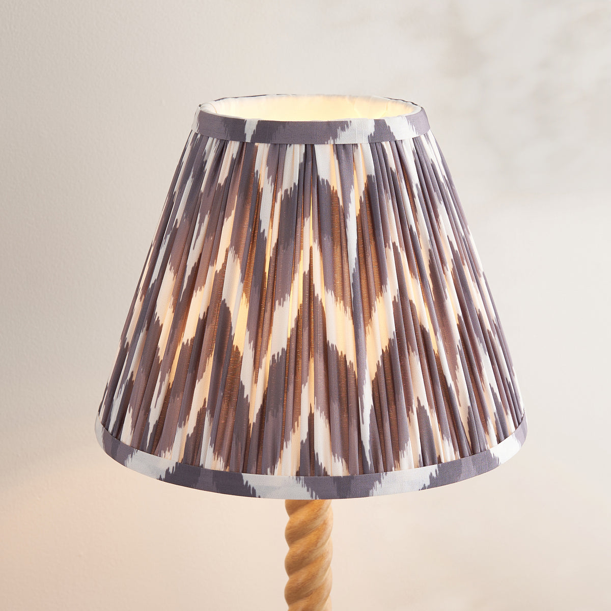 Close-up of the pleated grey and cream zigzag ikat shade above the oak twisted stem