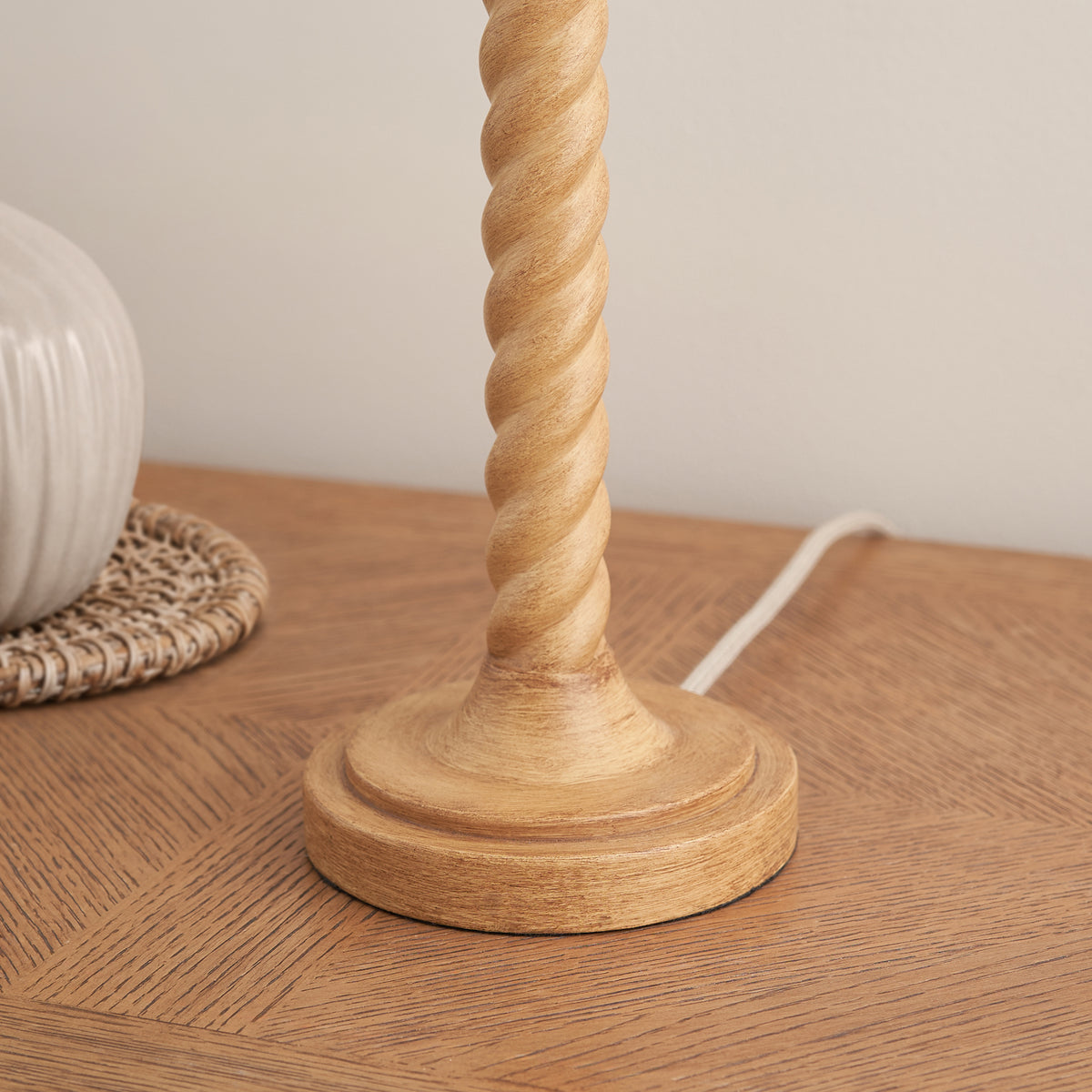 Detail of the round oak effect table lamp base and twisted column on a wooden surface