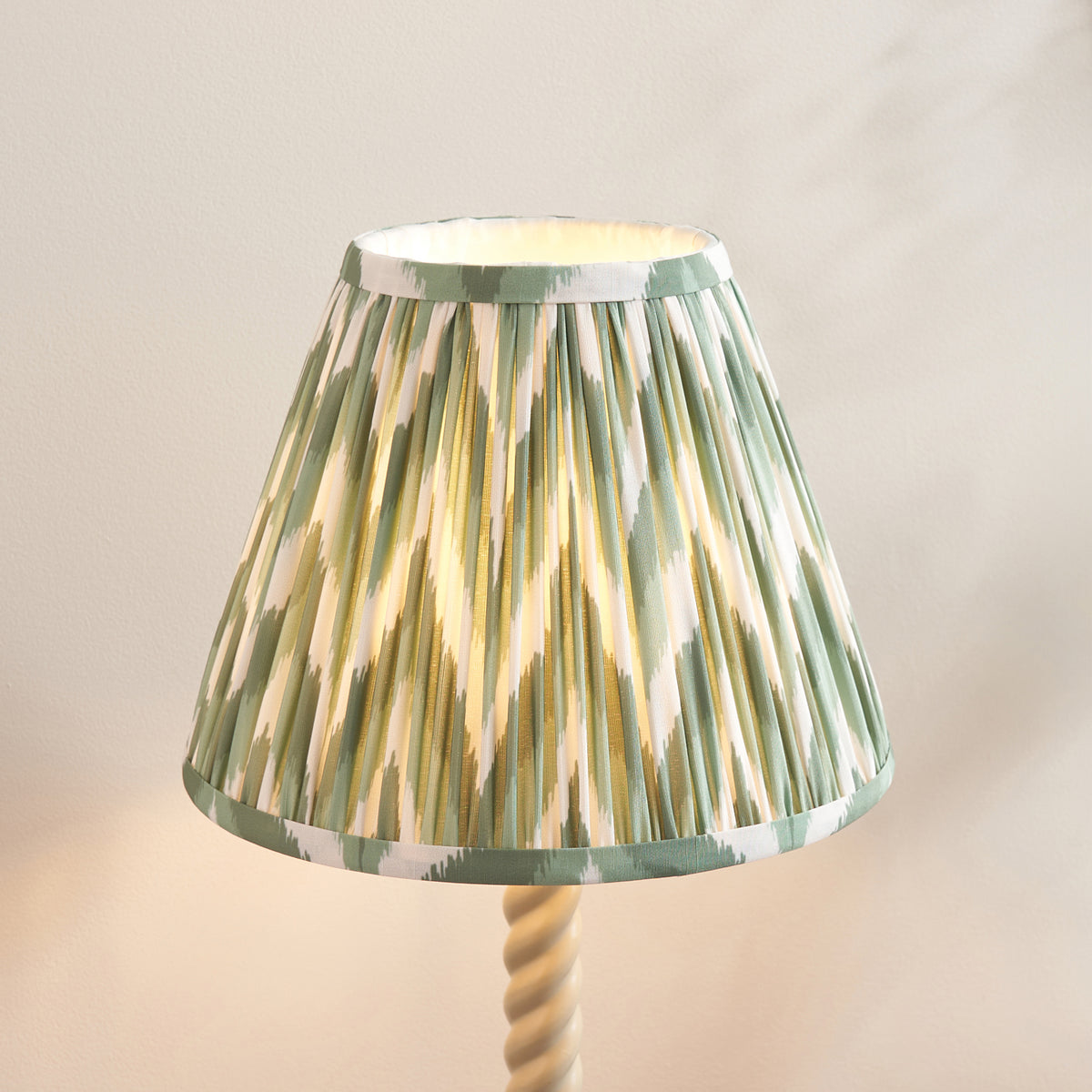 Close-up of the pleated green and cream zigzag shade above the almond white twisted stem