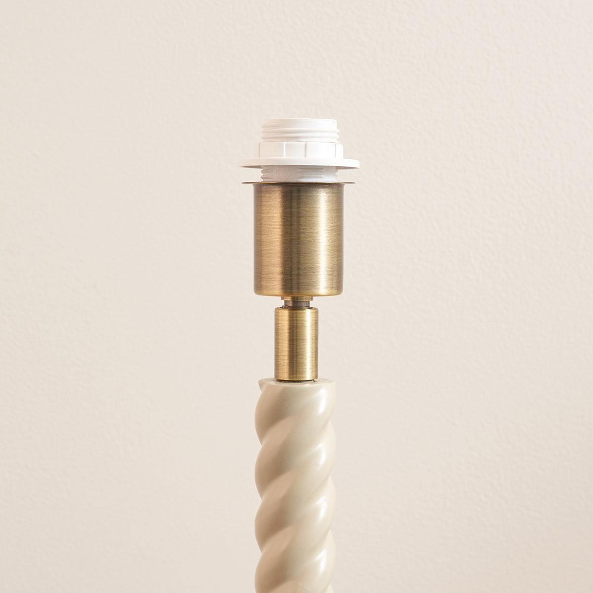 Detail of the brass lamp holder above the almond white twisted stem of the Twist & Ikat lamp