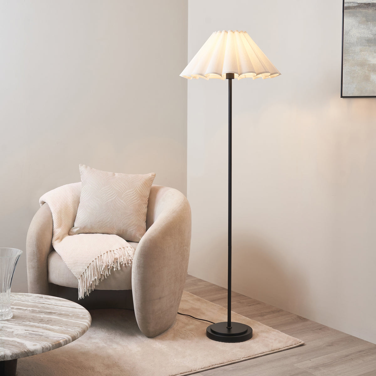 Scalloped-shade Arlo & Ayla floor lamp lit next to a cream boucle armchair in a living room