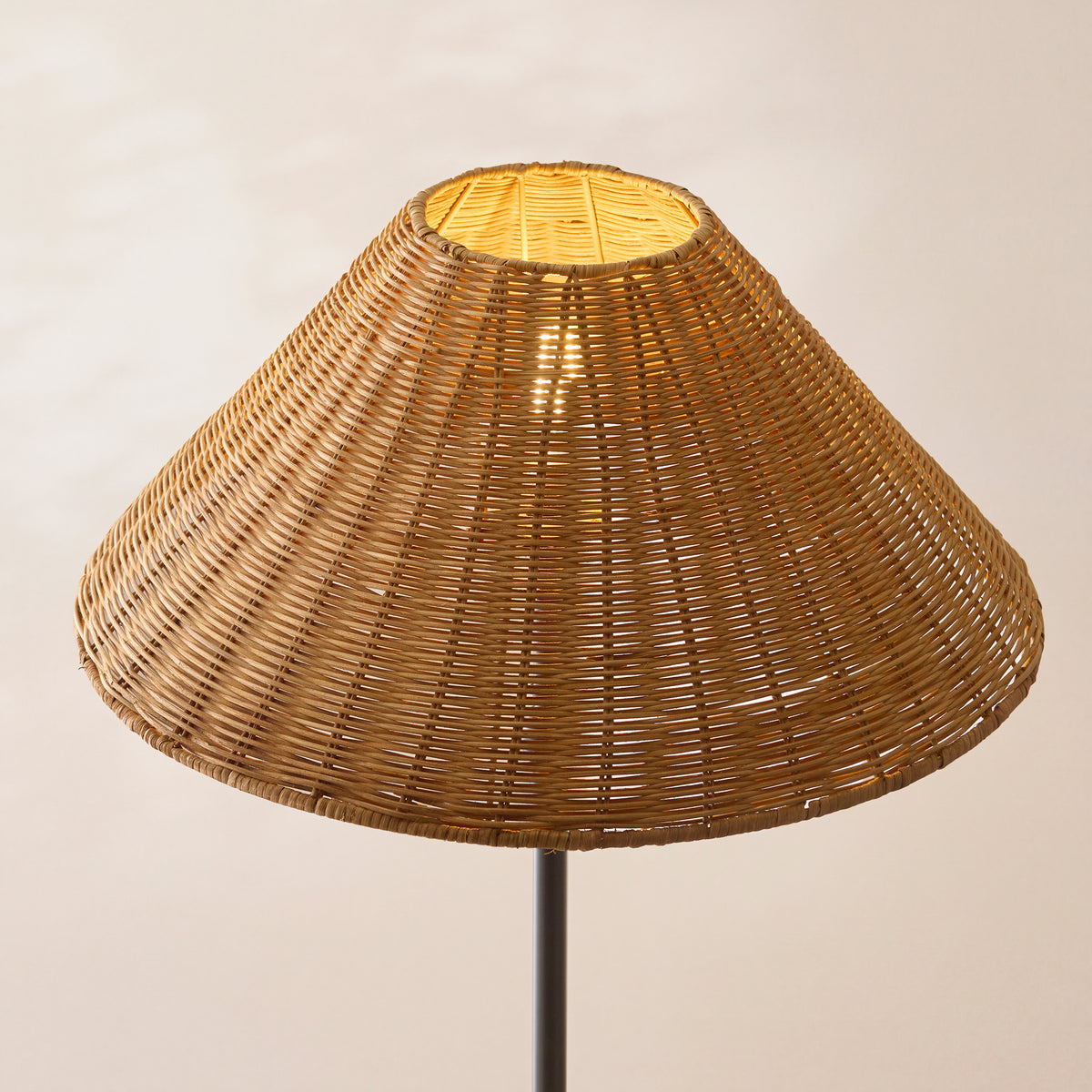 Close-up of the lit brown rattan woven shade on the Arlo matt black floor lamp