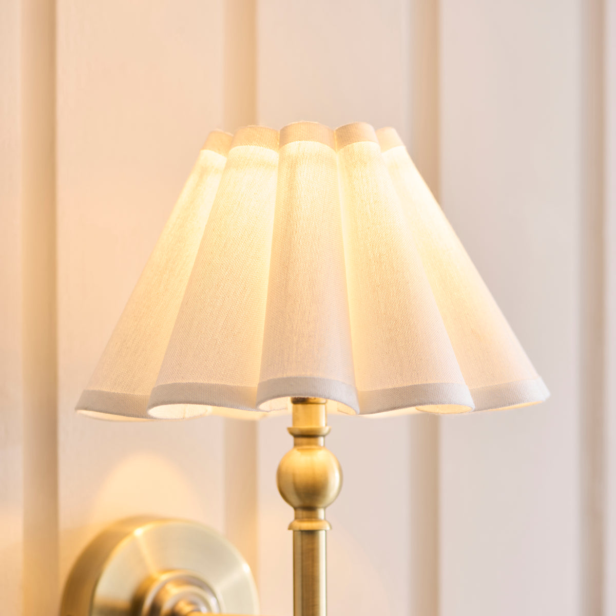 Close-up of the scalloped white linen shade and brass ball detail on the Sylvie wall light
