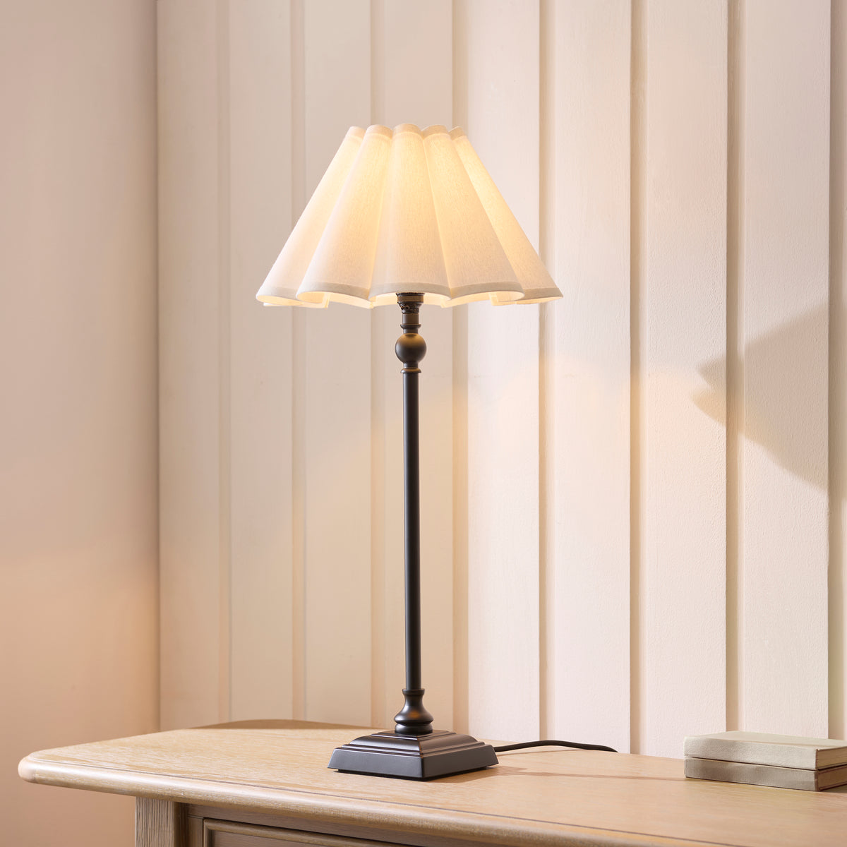 Sylvie black table lamp glowing on a console table against cream panelled walls