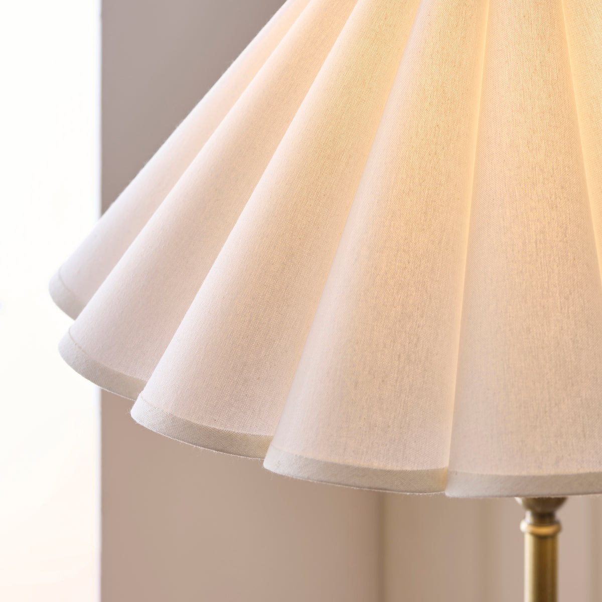 Close-up of the scalloped white linen shade above the brass stem of the Sylvie floor lamp