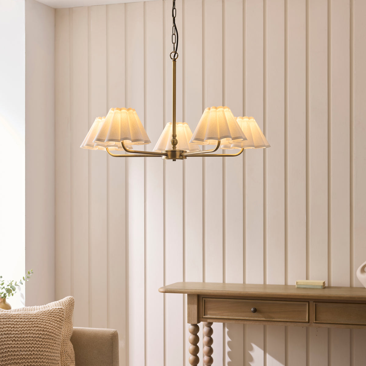 Sylvie antique brass pendant with scalloped shades lit above a wooden console table in a panelled living room