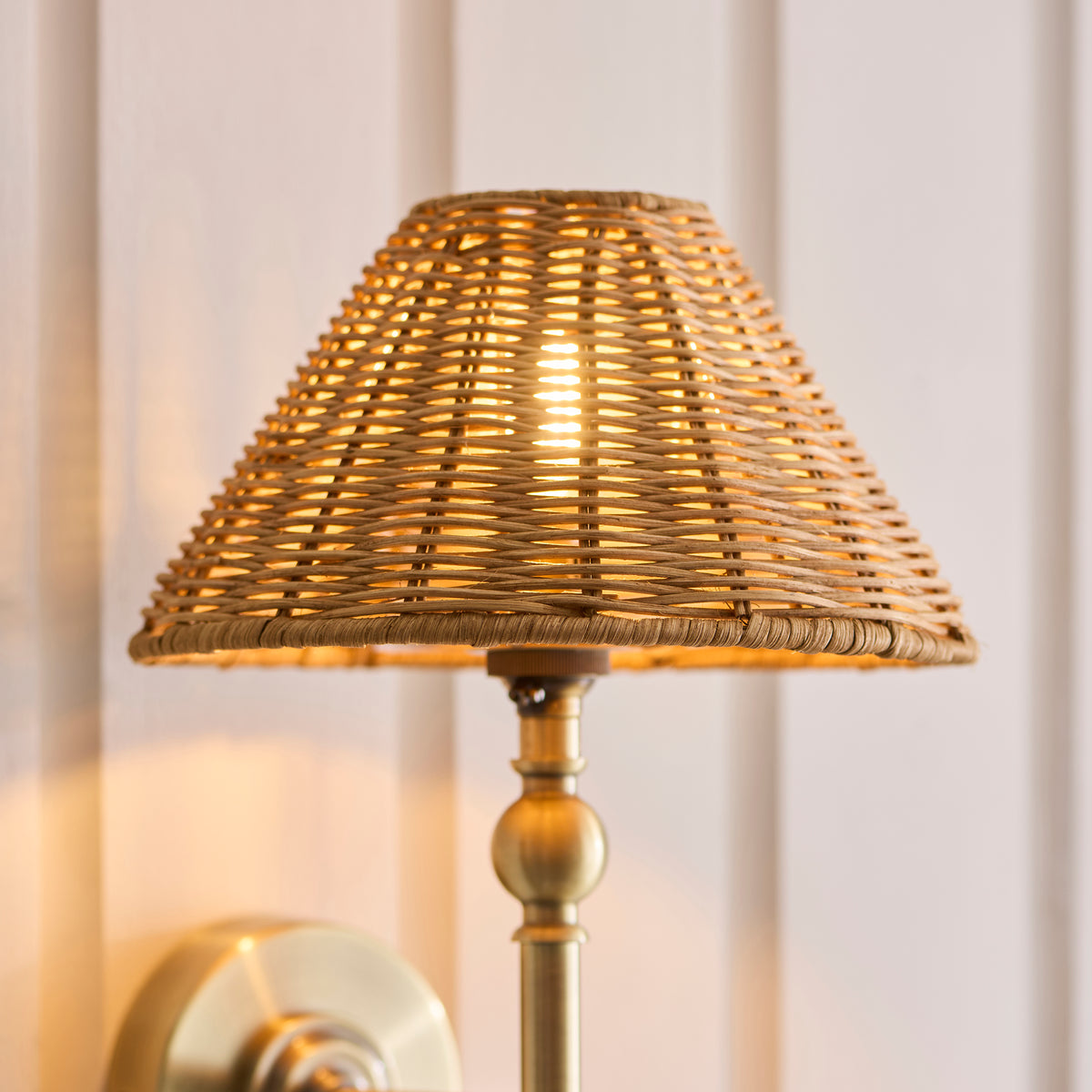 Detail of the Jericho light's woven rattan shade and antique brass stem, warmly lit