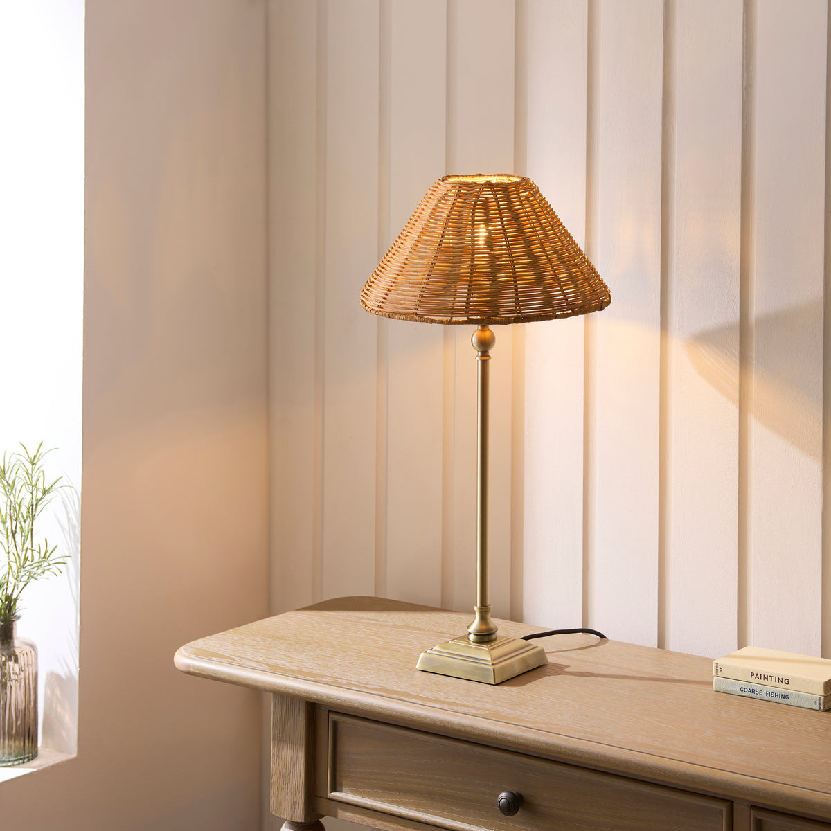 Jericho brass rattan table lamp glowing on a painted wooden chest of drawers