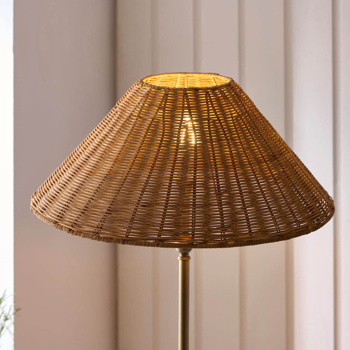 Close-up of the Jericho floor lamp's woven brown rattan coolie shade glowing warmly