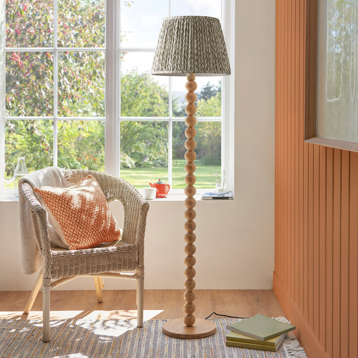 Cane & Leaf bamboo floor lamp glowing in a sunlit corner with rattan chair and books