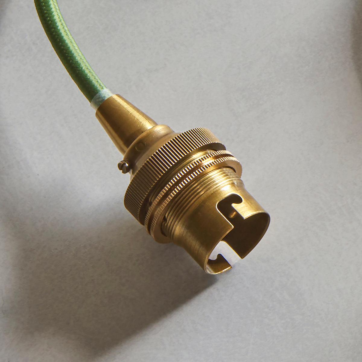 Close-up of the Eltham pendant's brass bayonet lampholder and green fabric flex