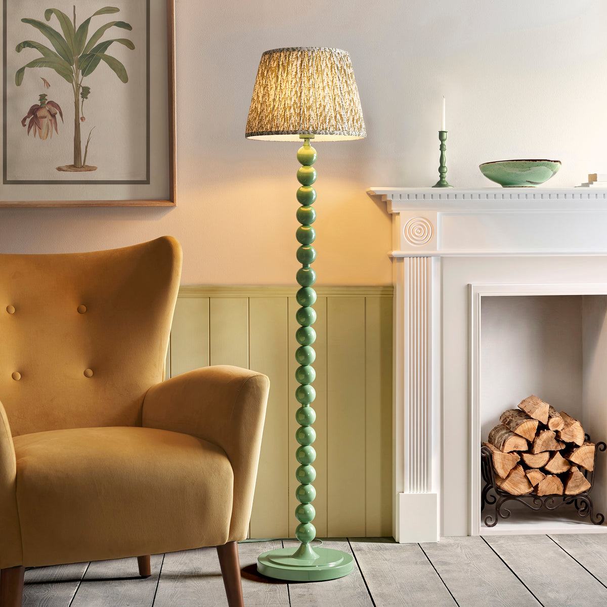 Higgledy & Leaf green floor lamp lit beside a mustard armchair and white fireplace in a panelled sitting room