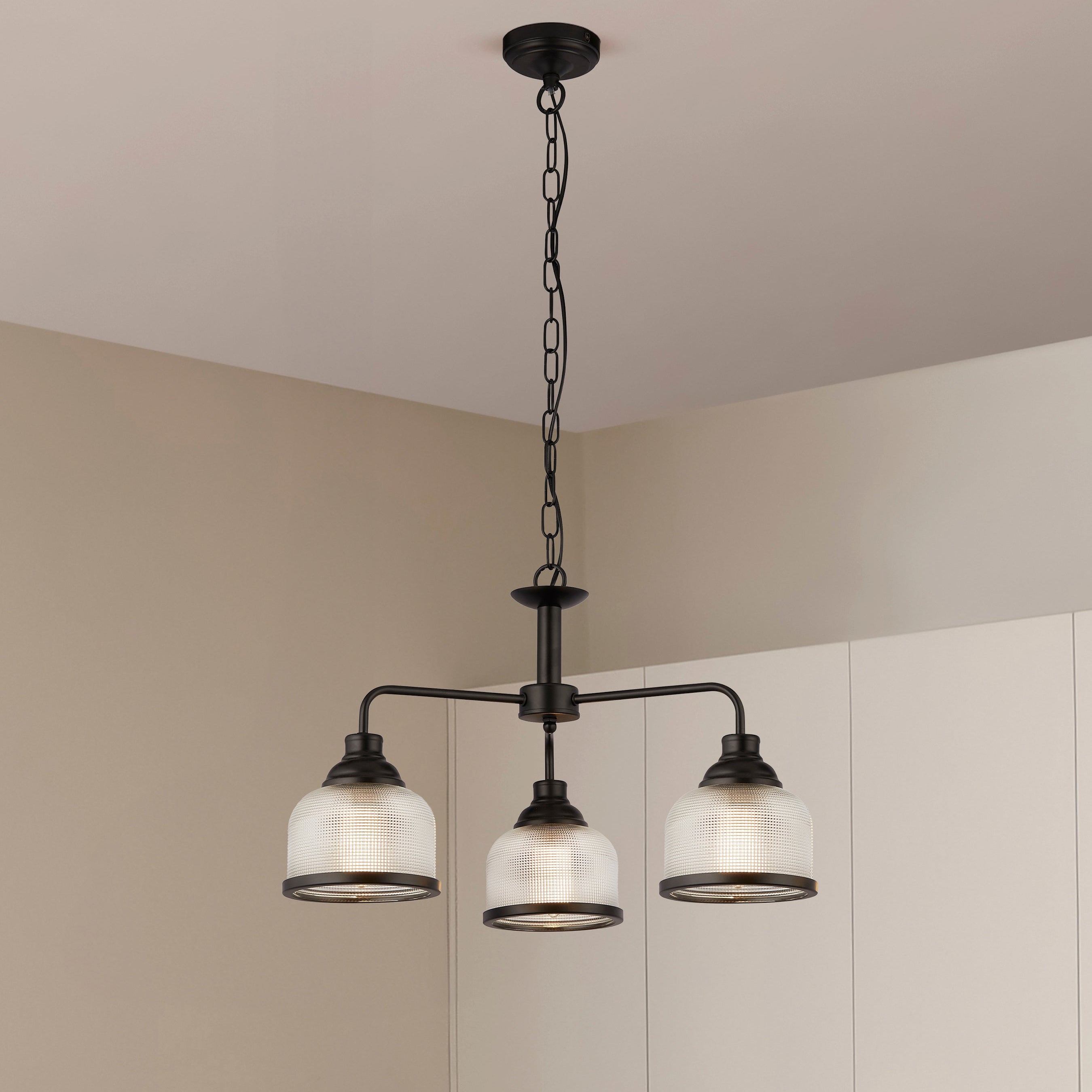 Modern pendant light fixture hanging in a kitchen with white cabinets.