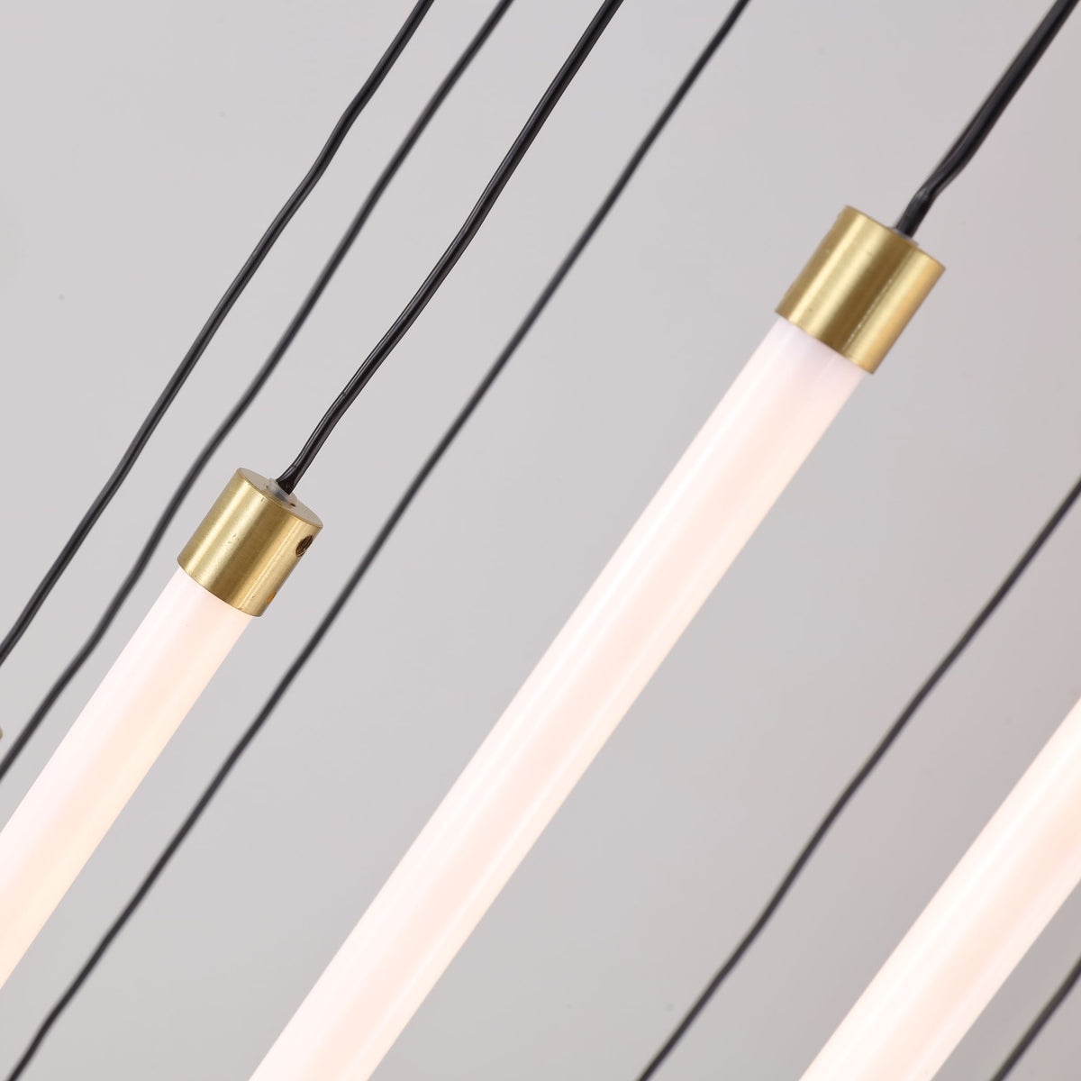 Close-up of the Flare pendant's brass caps and frosted white LED tubes on black cables