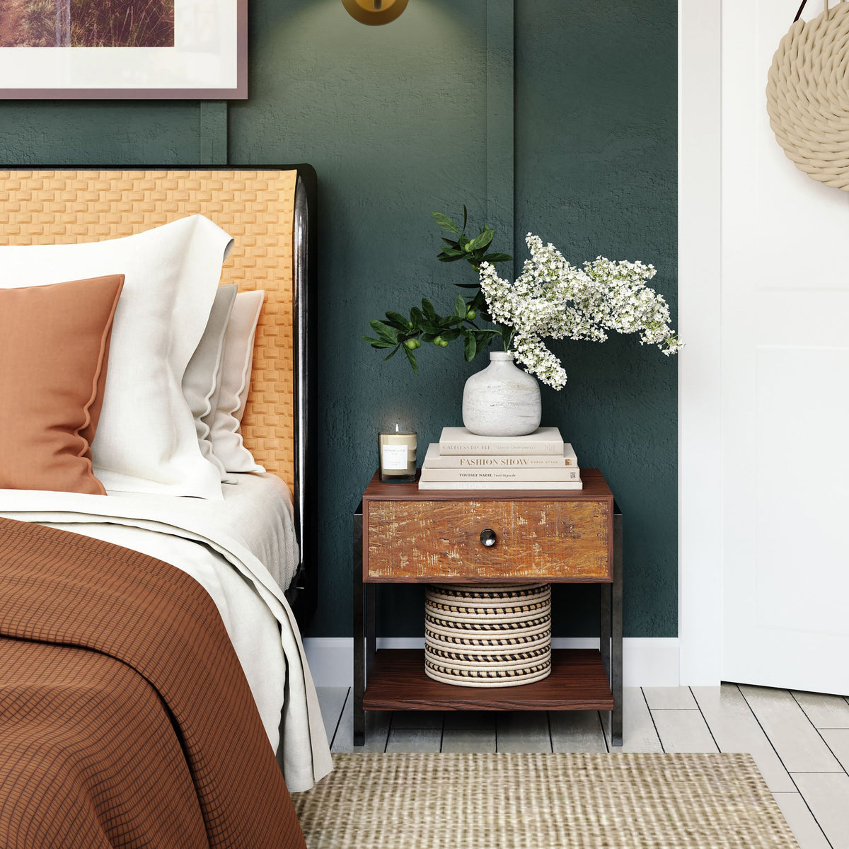 Danish gold wall light in a green-walled bedroom above a wooden bedside table with vase and books