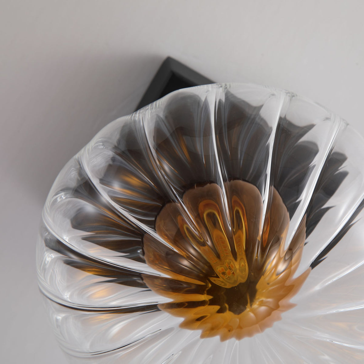 Close-up of Sunbeam petal-ribbed glass disc and amber centre on a matt black backplate