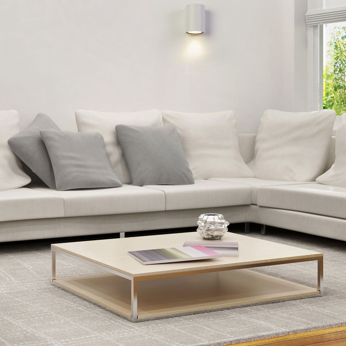Cyls white wall light above a cream corner sofa and low coffee table in a bright lounge
