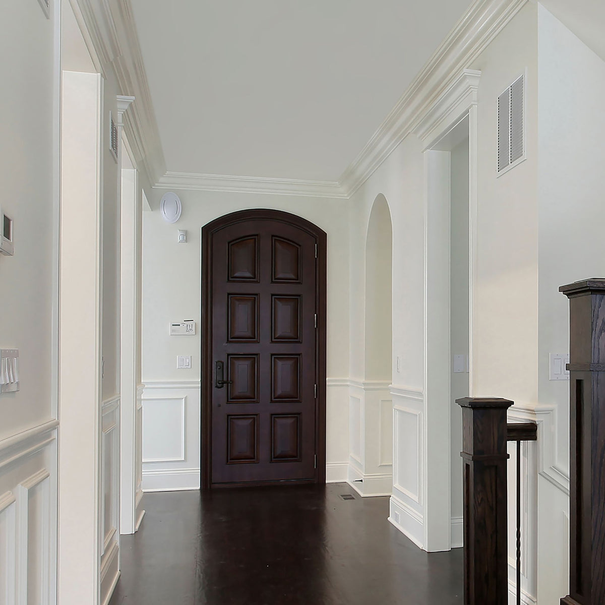 Classic white hallway with panelled walls and an arched dark wood door suited to Stellaris ceiling light