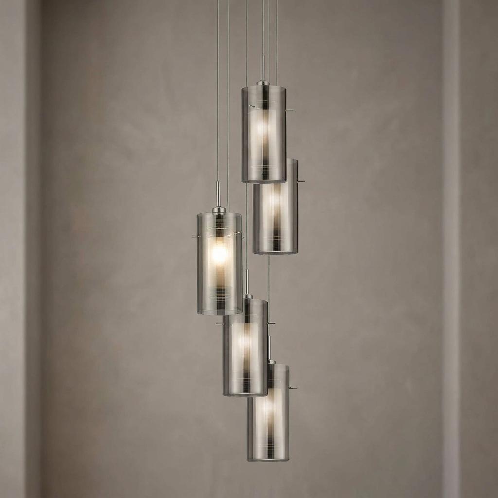 Five staggered cylindrical pendant lights with smokey and frosted glass shades against a grey wall.