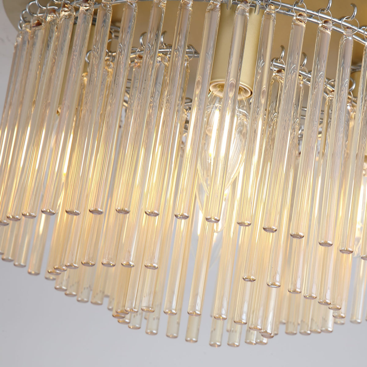 Detail of Swizzle champagne glass rods and gold plate with a warm filament lamp behind