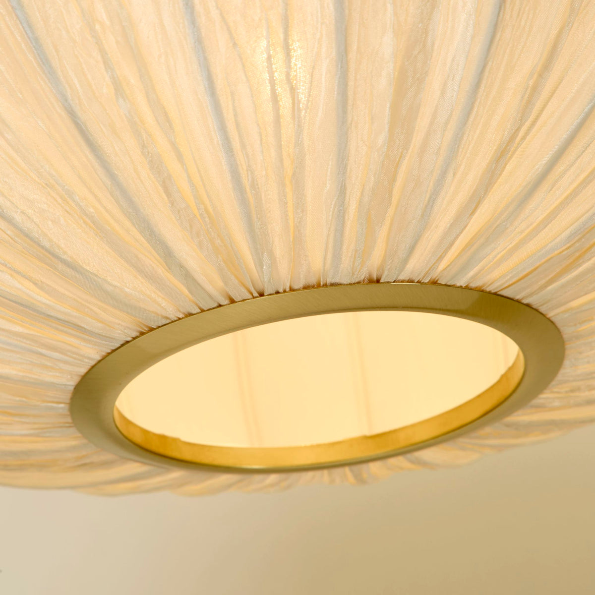 Close-up of the Bonnie pendant's satin brass base ring and pleated ivory fabric