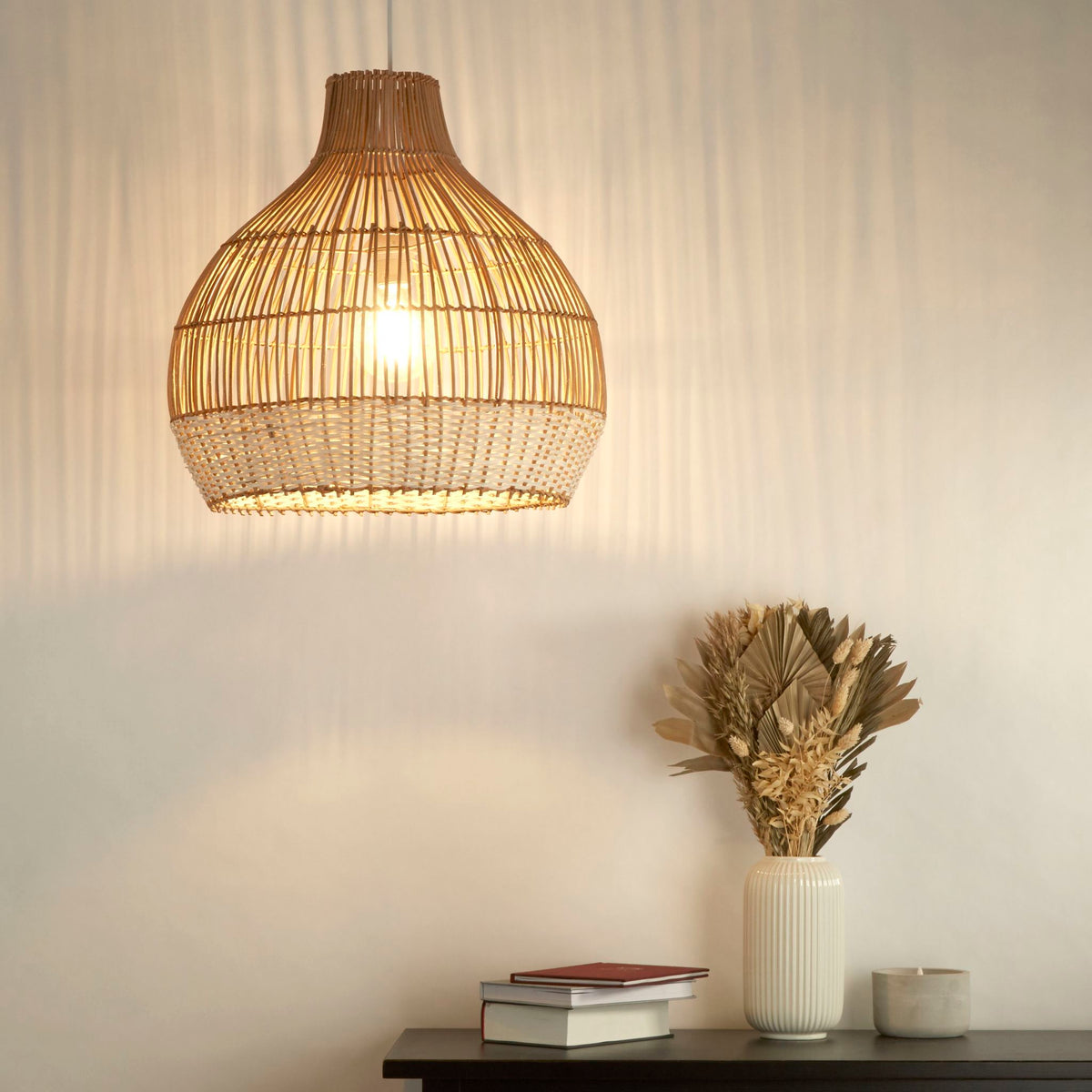 Bali rattan pendant beside a black console with dried grasses in a ribbed vase