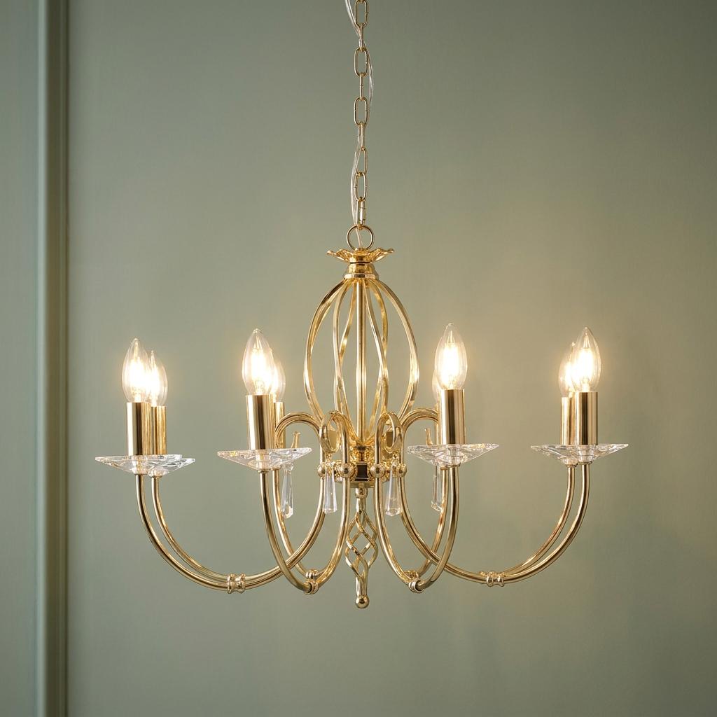 Aegean 8 light polished brass chandelier with candle bulbs and crystal accents against a sage green wall.