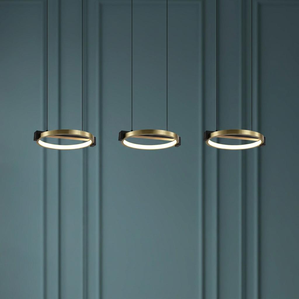 Three gold and black circular LED pendant lights glowing against a dark teal paneled wall.